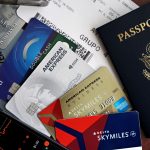 Passaporte, cartões e cartão de embarque dispostos sobre uma superfície, representando viagens e créditos de fidelidade.