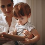 Mãe e criança usam juntas um smartphone dentro de casa.