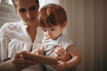 Mãe e criança usam juntas um smartphone dentro de casa.