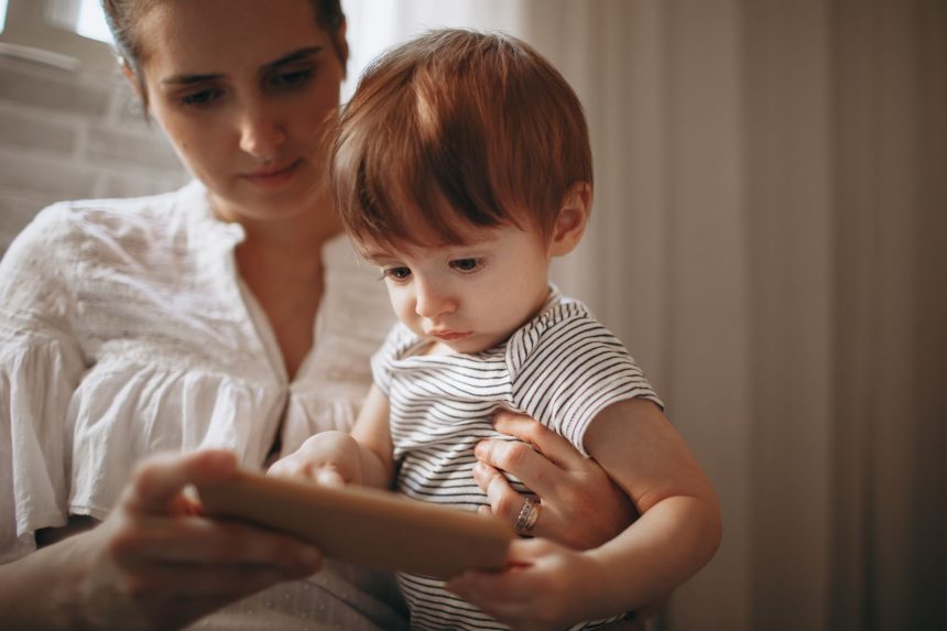 Mãe e criança usam juntas um smartphone dentro de casa.