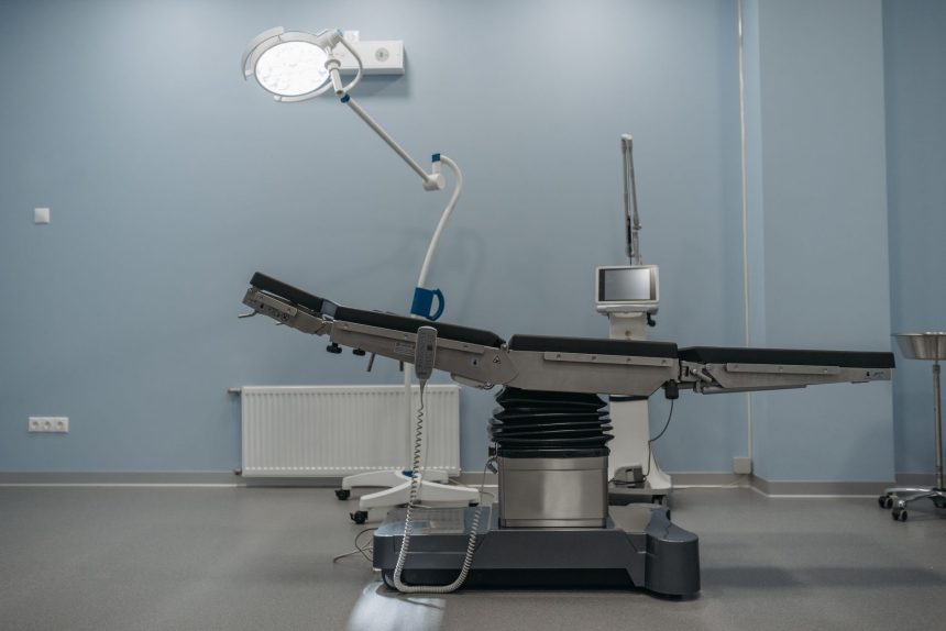 Sala de cirurgia vazia, com mesa operatória e equipamentos médicos modernos.