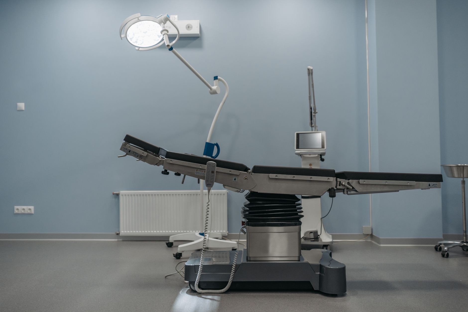 Sala de cirurgia vazia, com mesa operatória e equipamentos médicos modernos.