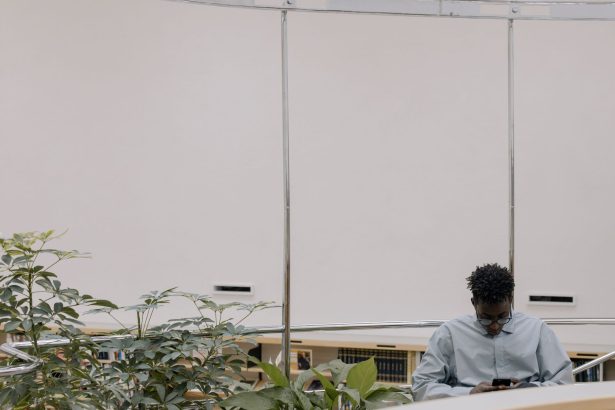 Homem usa um smartphone em um ambiente interno moderno cercado por plantas.