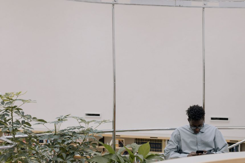 Homem usa um smartphone em um ambiente interno moderno cercado por plantas.